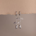 Dangling Silver earrings shaped like roses on a beige background