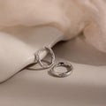 Silver hoop earrings with small diamonds on a beige fabric background