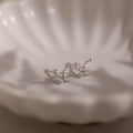Silver butterfly-shaped diamond earrings on a soft white background