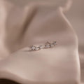 Pair of silver star stud earrings with clear stones on a beige fabric background