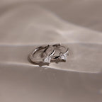 Silver huggie earrings with two diamond stones on a beige background