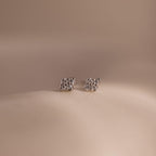 Pair of silver kite-shaped earrings with embedded stones on a beige background