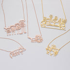 Five Kids Drawing Necklaces—shaped like families, a lion, a cat, and people on a tandem bicycle—are displayed as unique Wearable Art, perfect for personalized gifts or custom jewelry inspired by children's drawings.