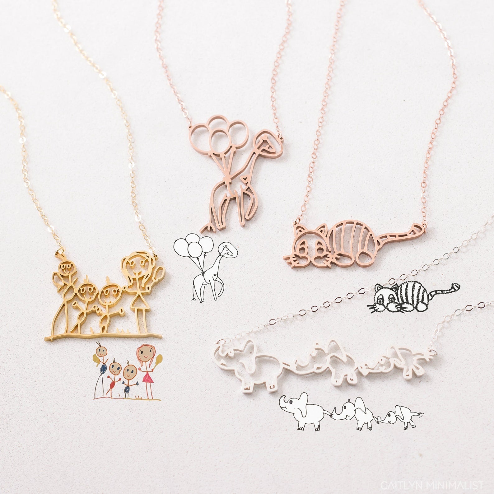 The Kids Drawing Necklace features four unique necklaces with animal and family designs, displayed next to matching line sketches—each piece is a one-of-a-kind, wearable work of art and an ideal personalized gift.