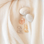 The Linked Necklace & Earrings Set displayed beside two smooth stones on crinkled white fabric—an elegant arrangement, perfect as an Anniversary Gift.