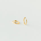 Two gold hoop diamond earrings on a light gray background