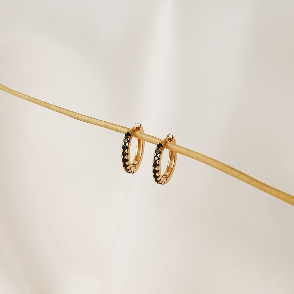 Black Onyx Hoops Bundle: gold hoop earrings with small black onyx stones, displayed on a thin beige stick against a light background.