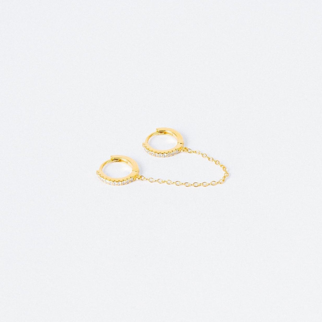 The Diamond Chain Earrings Set features two small gold hoops linked by a delicate chain, each adorned with clear stones for extra sparkle.