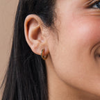 Close-up of a woman smiling, wearing Black Onyx Hoops Bundle—small gold hoops with black stones.