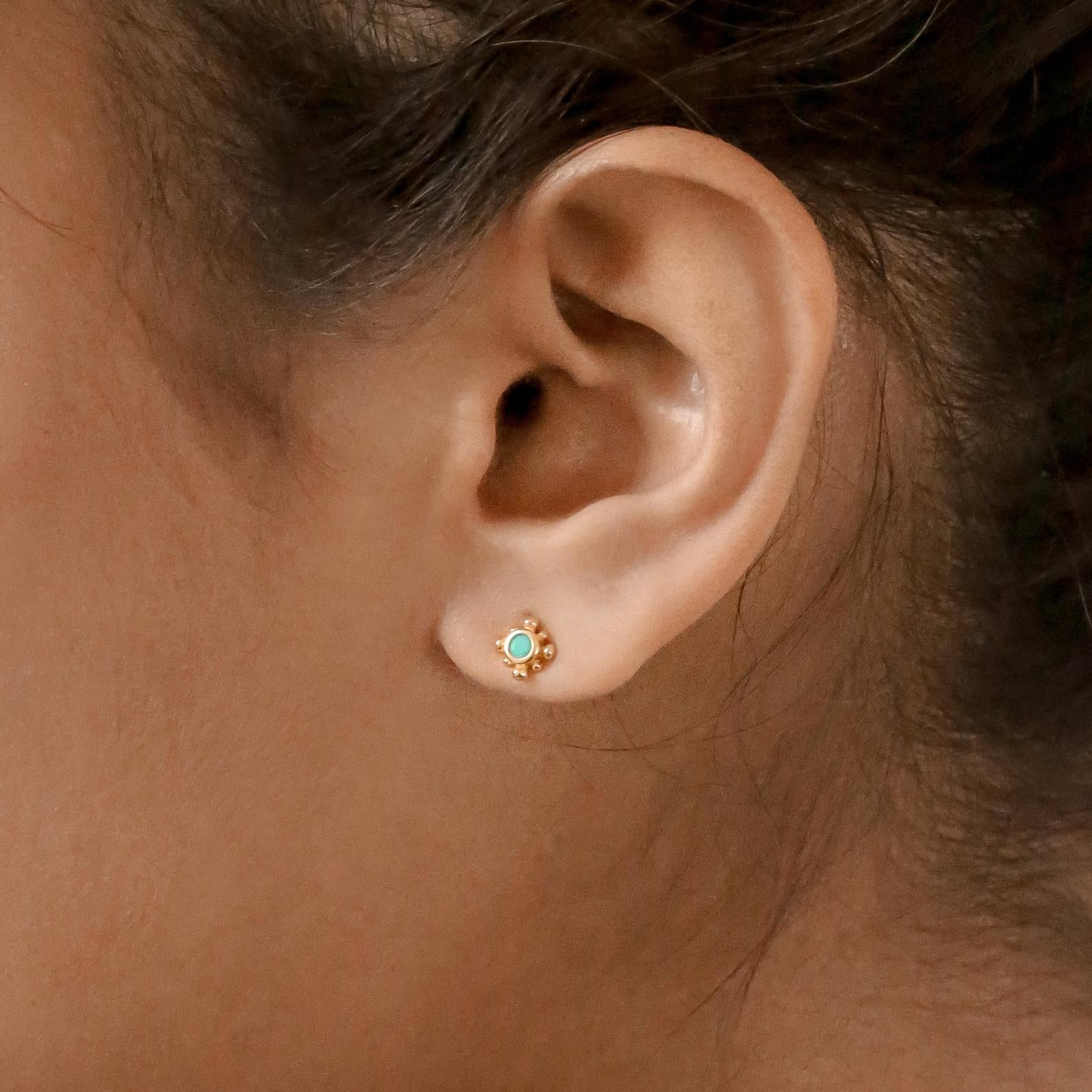 Close-up of a woman's ear wearing a small stud from the Boho Turquoise Earring Set, featuring a gold finish and turquoise center that blends bohemian charm with timeless style.