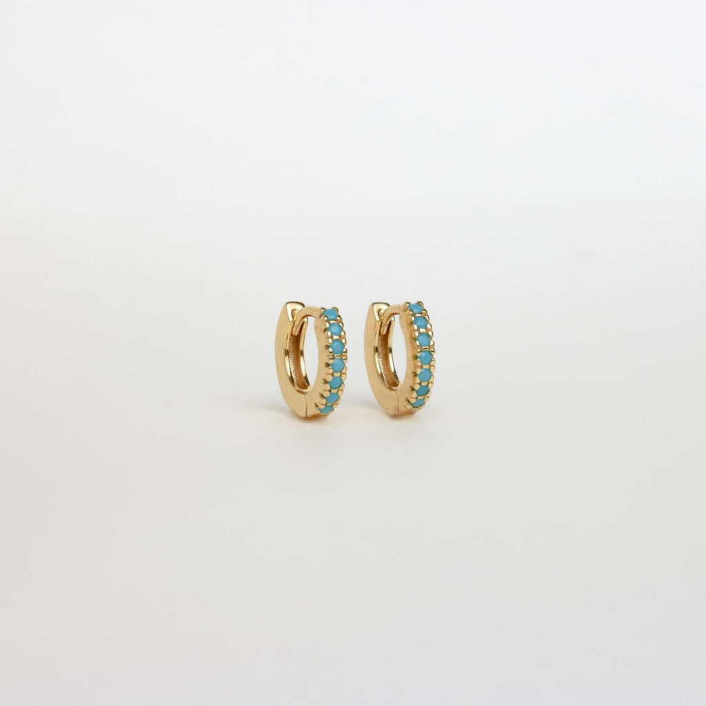 The Boho Turquoise Earring Set features small gold hoops lined with turquoise stones, adding a bohemian touch to any look. Shown on a white background, this set is ideal for those who adore unique turquoise jewelry.