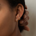 Close-up of a model’s ear adorned with two Amelia Duo Huggies in 18K Gold. Each huggie earring features a sleek double-band design, with one band polished in gleaming gold and the other pavé-set with tiny shimmering crystals. 