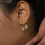 Close-up of an ear wearing the Boho Turquoise Earring Set, featuring gold hoops with star and blue crescent moon charms for a bohemian vibe.