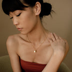 A woman wearing a Padlock Paperclip Necklace and a strapless top looks down with her hand on her shoulder.