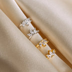 The Giana Marquise Huggies, featuring elegant marquise-cut stones, are displayed on soft beige fabric and paired with subtle earrings for a refined look.