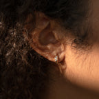 Close-up of a person's ear wearing Giana Marquise Huggies in Sterling Silver, featuring a marquise-shaped detail—ideal for those who love subtle earrings.