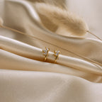 The Giana Marquise Huggies are shown on soft beige satin with dried grass, creating a subtle look that's perfect for everyday elegance.