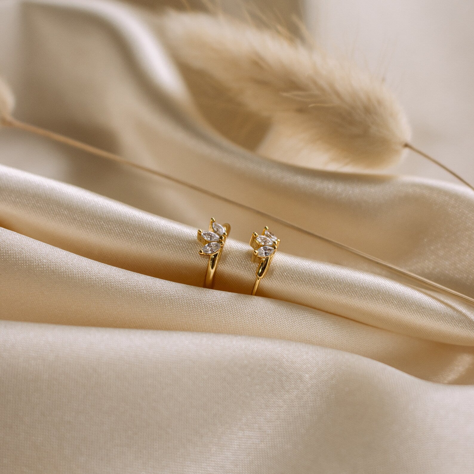 The Giana Marquise Huggies are shown on soft beige satin with dried grass, creating a subtle look that's perfect for everyday elegance.