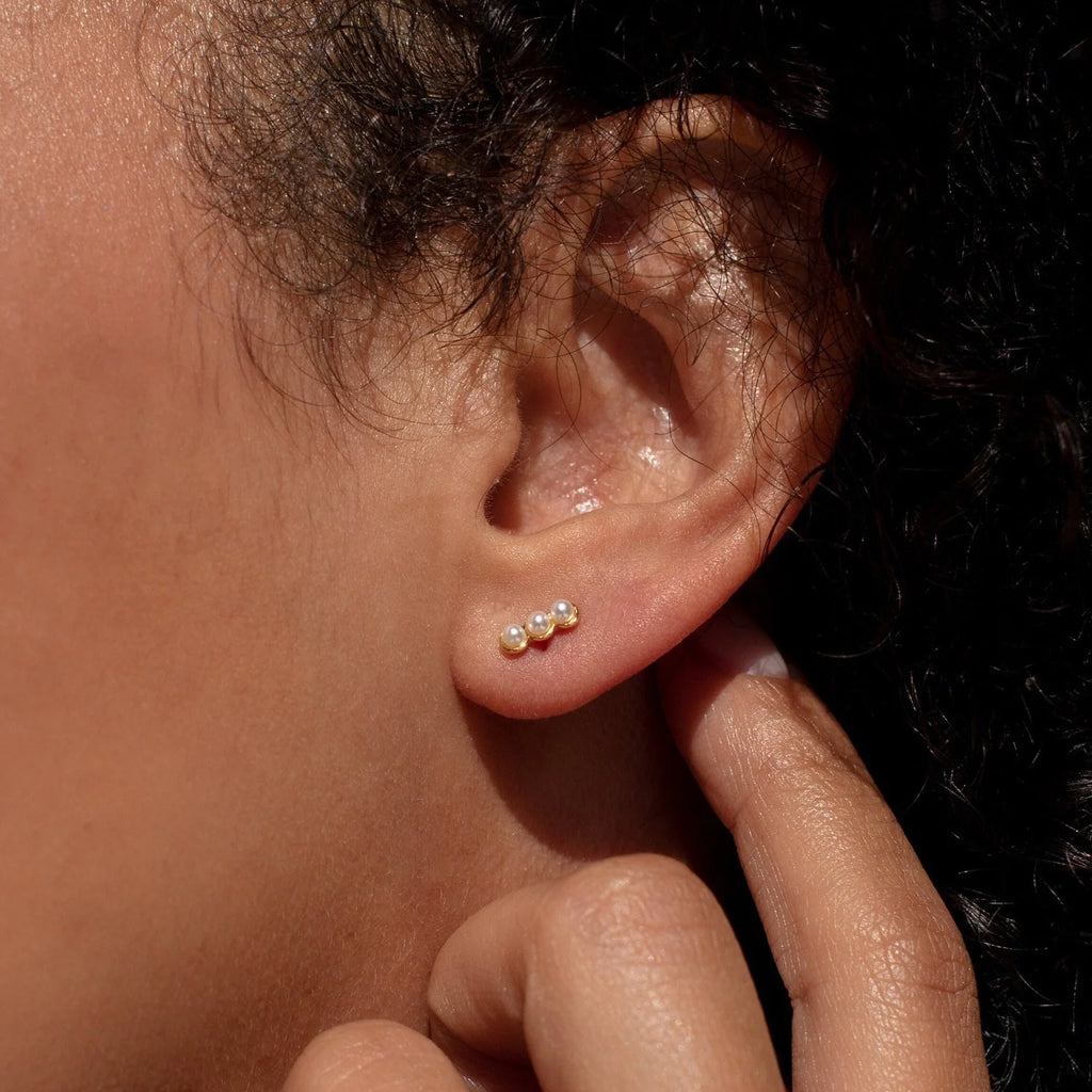 A person’s ear with a finger in their ear, showcasing the elegant Pearl Earrings Set.