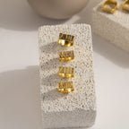 Four Bold Name Rings engraved with Emily, Noah, Zoe, and Easion displayed on a textured stone block—a striking personalized jewelry collection perfect for making a statement.