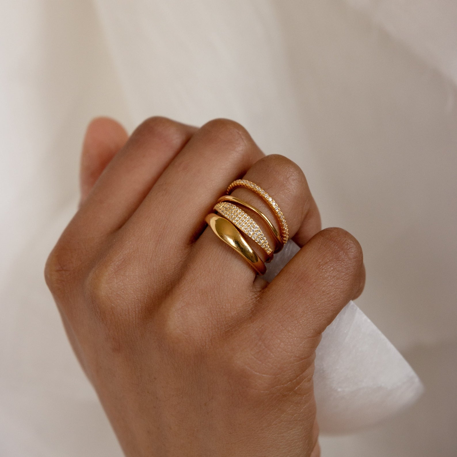 Hand wearing the Duo Form Ring Set stacked with pavé and textured gold bands for a layered look.