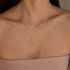 A woman wearing the Marquise Station Necklace, featuring marquise-shaped stones as delicate charms on a dainty chain, paired with a strapless nude top.