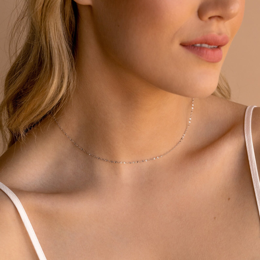A woman wears a delicate silver Josephine Chain Necklace choker with a white spaghetti strap top, making it perfect wedding jewelry.