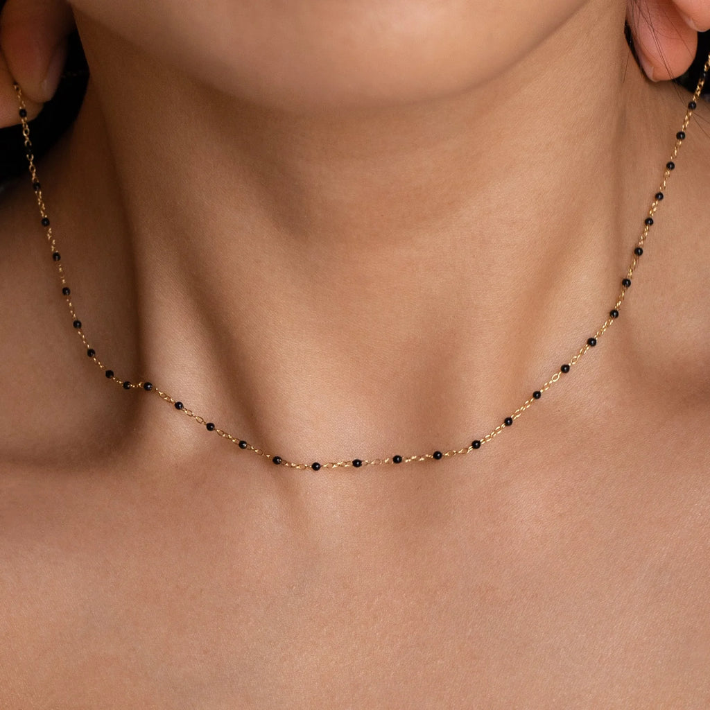 Close-up of a woman wearing the Onyx Necklace Set, a delicate gold chain with small black and gold beads—perfect for layering and adding elegance to any minimalist look.