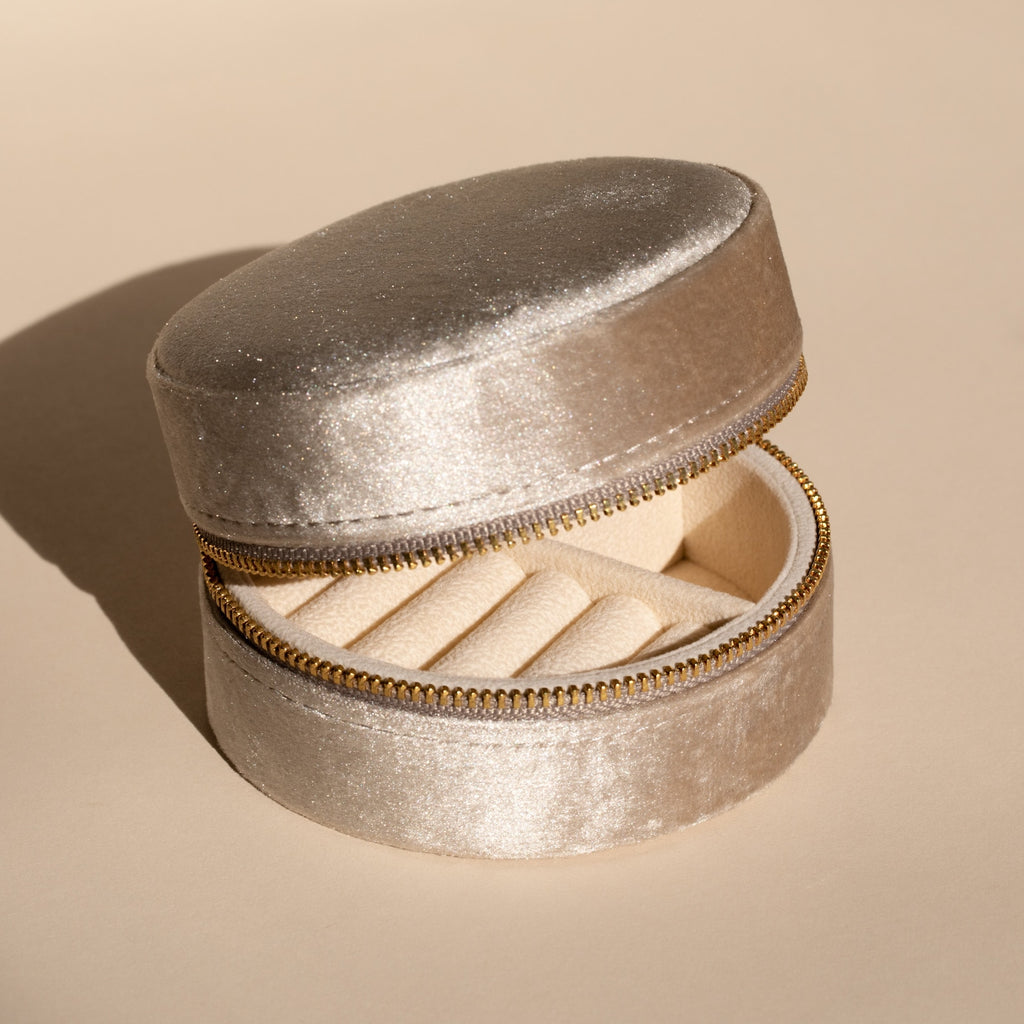 The Round Velvet Jewelry Case in light beige features a zipper and organized ring compartments, making it an ideal minimalist jewelry box and travel organizer.