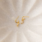 The Opal Drop Earrings Set features gold crescent-shaped earrings with delicate opal accents, displayed on a soft, light-textured background—ideal for layering with other jewelry pieces.