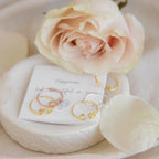 The Dainty Duo Initial Ring, shown on a card with a pale pink rose and petals, makes a perfect personalized gift or meaningful anniversary present.