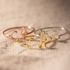 The Nella Duo Initial Ring—engraved with custom initials—rests on textured beige fabric, showcasing a personalized jewelry piece and a thoughtful anniversary gift.