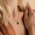 Close-up of the Agate Pendant Necklace, a handmade piece with a green agate pendant on a gold chain, worn by a woman in a brown top.
