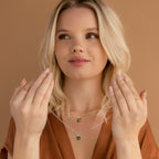 A woman in a brown top holds up two Agate Pendant Necklaces with green stone pendants against a beige background.
