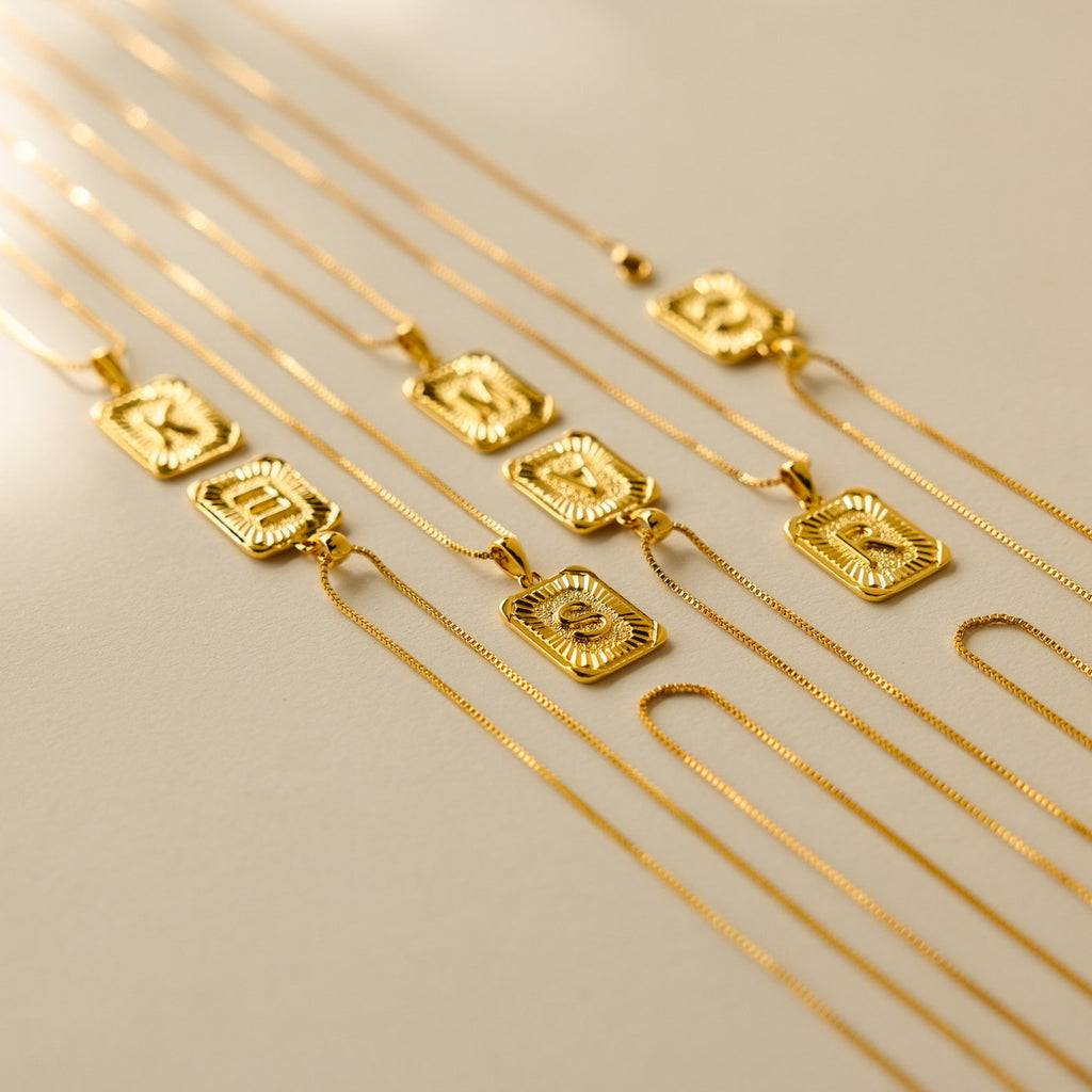 Initial Rectangle Pendant Necklaces are neatly arranged on a light surface, featuring striking sun designs and customizable options for personal initials.