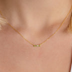 A close-up of the Initial Morse Birthstone Necklace, featuring a small horizontal bar pendant with Morse code on a person's neck.