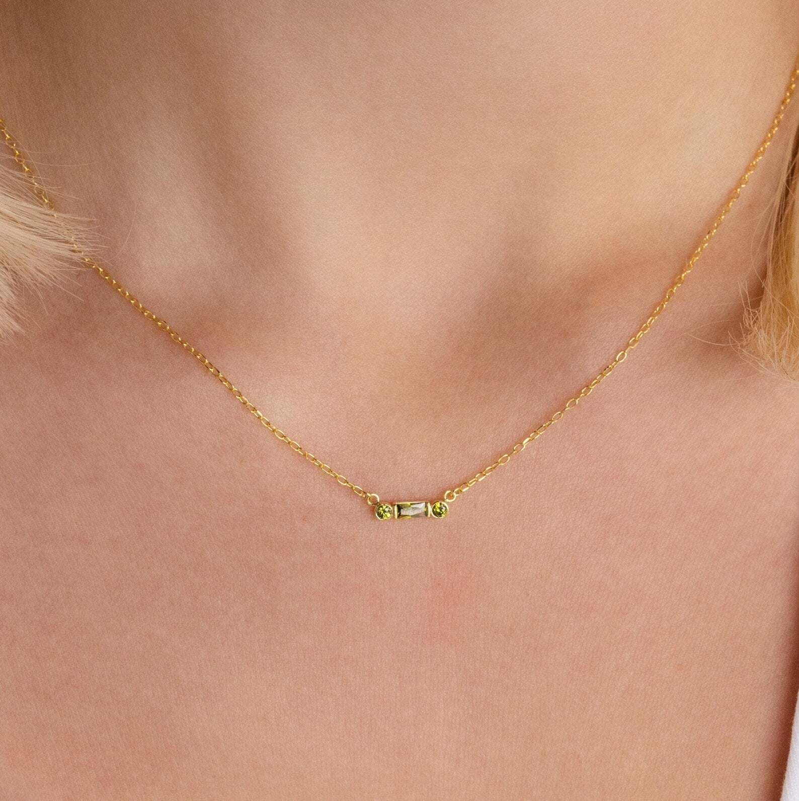 A close-up of the Initial Morse Birthstone Necklace, featuring a small horizontal bar pendant with Morse code on a person's neck.