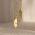 Two Newsletter Oval Tag Necklaces—one engraved with the letter A and the other with 444—create a timeless accessory set.