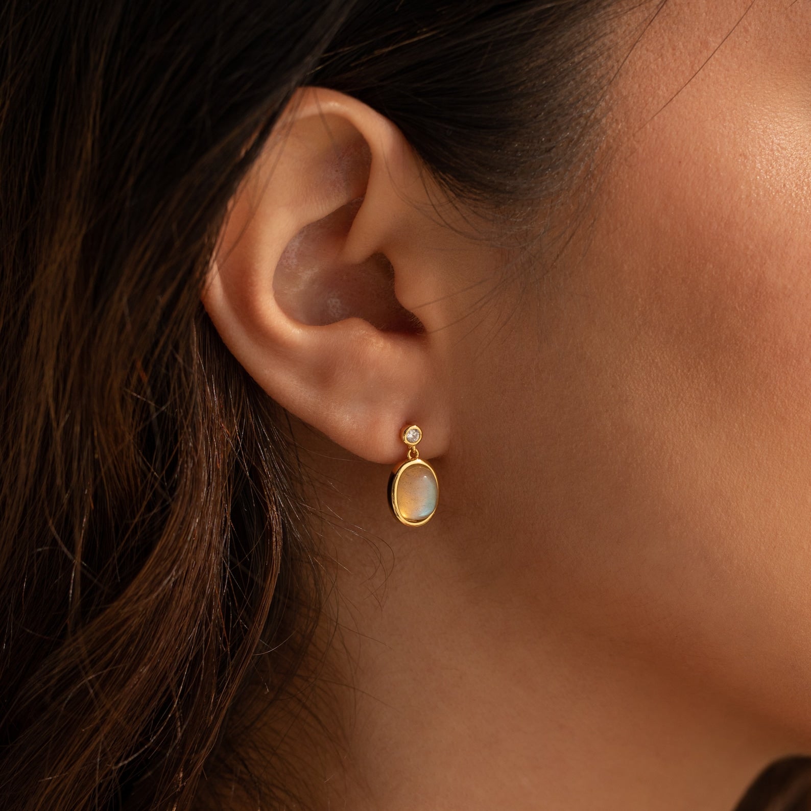 A close-up of a woman's ear adorned with Moonstone Drop Earrings.