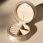 The Round Velvet Jewelry Case features beige velvet, a zipper closure, and compartments for rings and accessories—making it the ideal travel organizer for minimalists.