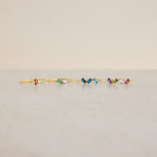 Five Cluster Baguette Birthstone Rings with colorful gemstones are arranged in a row on a light marble surface against a beige background, perfect as birthstone or personalized statement rings.