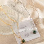 Two Agate Pendant Necklaces with green agate charms are displayed on glassware and a card that reads, "Happiness looks beautiful on you.