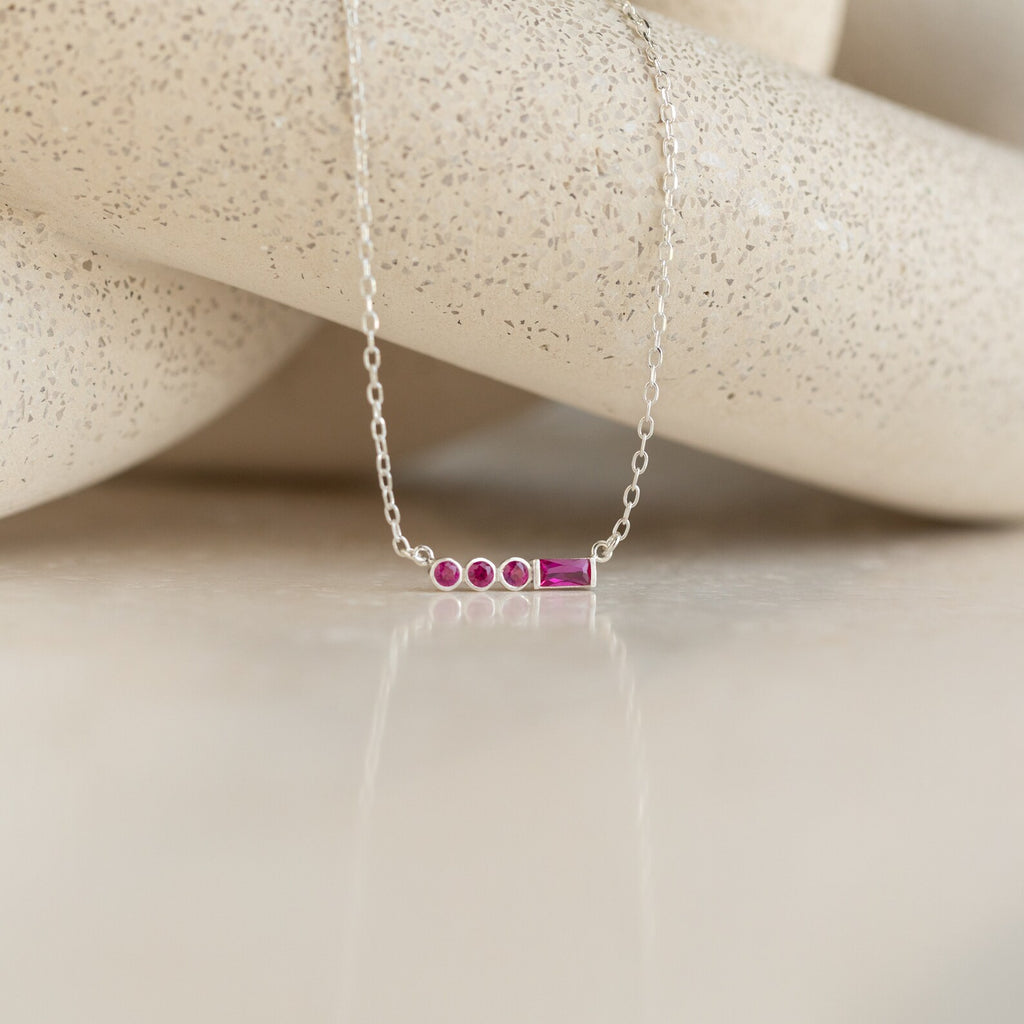 Initial Morse Birthstone Necklace with delicate pink gemstones, ideal as personalized jewelry. Shown on a neutral textured background.