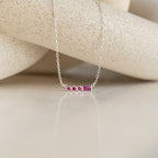 Initial Morse Birthstone Necklace with delicate pink gemstones, ideal as personalized jewelry. Shown on a neutral textured background.