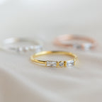 Initial Morse Code Ring, ideal for those who love personalized jewelry or want to pair it with a gold ring featuring a round center diamond and two rectangular side stones. Blurred rings in the background.