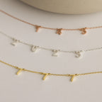 The Alice Spaced Number Necklace collection includes three minimalist necklaces with small number charms: 745 in rose gold, 2023 in silver (Birth Year Necklace), and 777 in gold, displayed on a beige background.