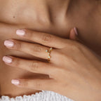 A hand with light pink nails wears the Constellation Ring on the ring finger, showcasing gold and small star-shaped accents for a celestial jewelry style.