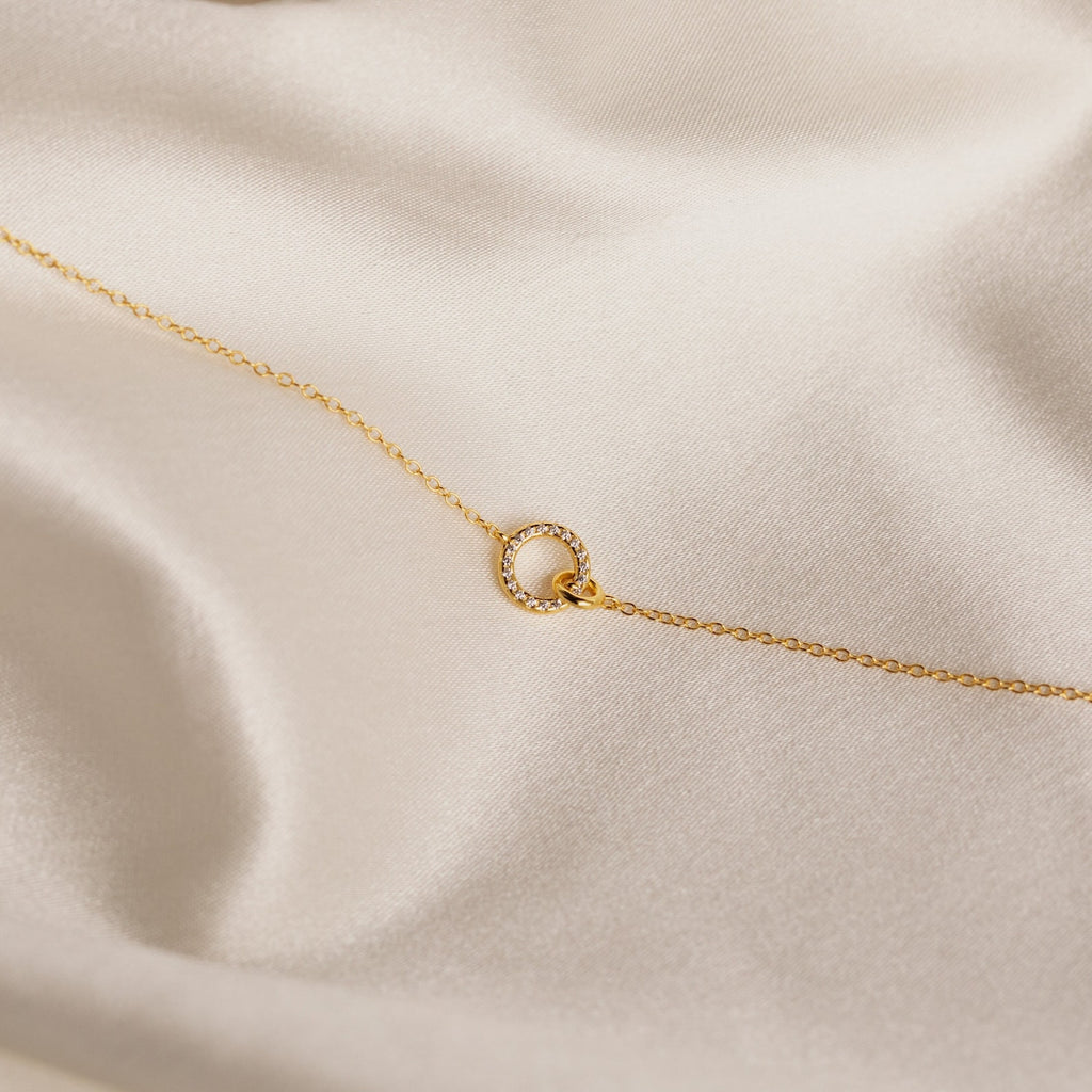 The Pave Interlocking Necklace features a gold chain with a delicate, circular pendant—it’s an elegant wedding gift and perfect for minimal diamond jewelry lovers.