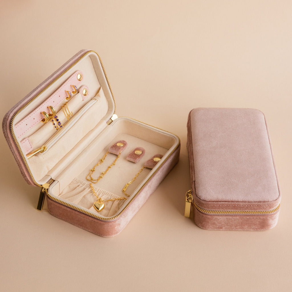 The Rectangle Velvet Jewelry Case in pink velvet opens to reveal assorted gold jewelry, with a matching closed case beside it on a beige surface—a stylish organizer for your treasured pieces.
