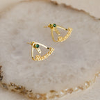 Featuring green birthstones and a personalized Hannah nameplate, the London Name Ear Jackets are stylish wrap-around earrings shown on a textured beige surface.